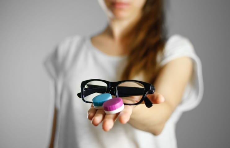 Woman holding glasses and contacts