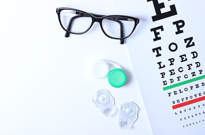 Contacts and eyeglasses on an eye chart