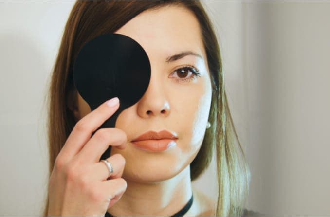 woman covering her eye during eye test