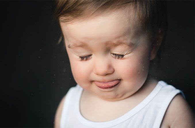 toddler closing eyes and sticking out tongue