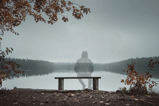 Translucent image of person sitting on a bench facing the lake