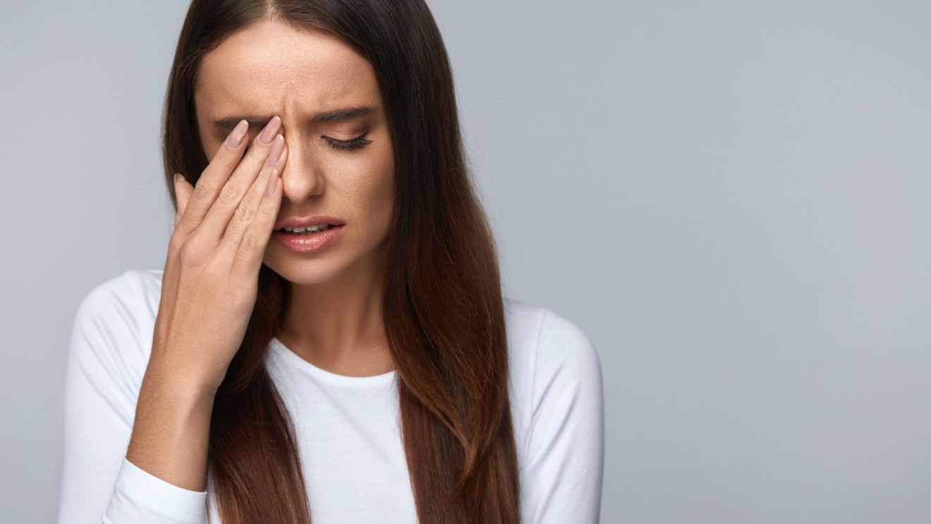 Woman holding eye in pain