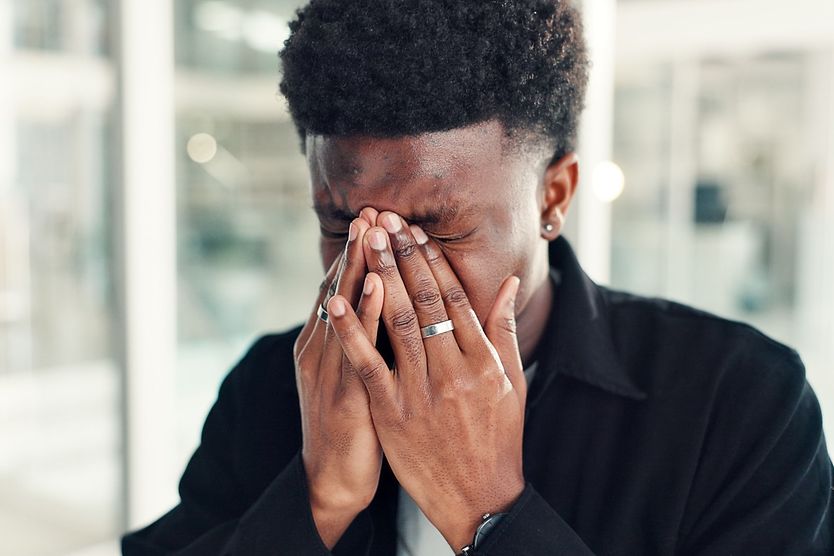 Young man with asthenopia (eye strain) rubbing his eyes.
