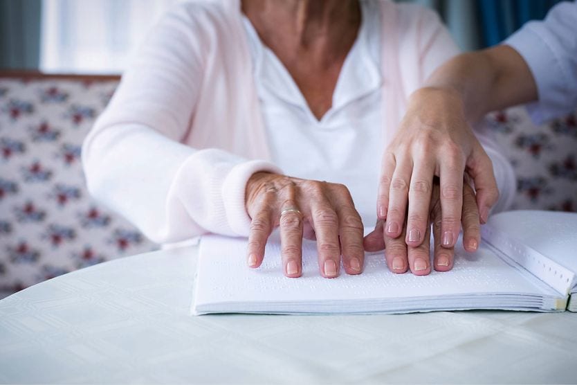older person reading braille
