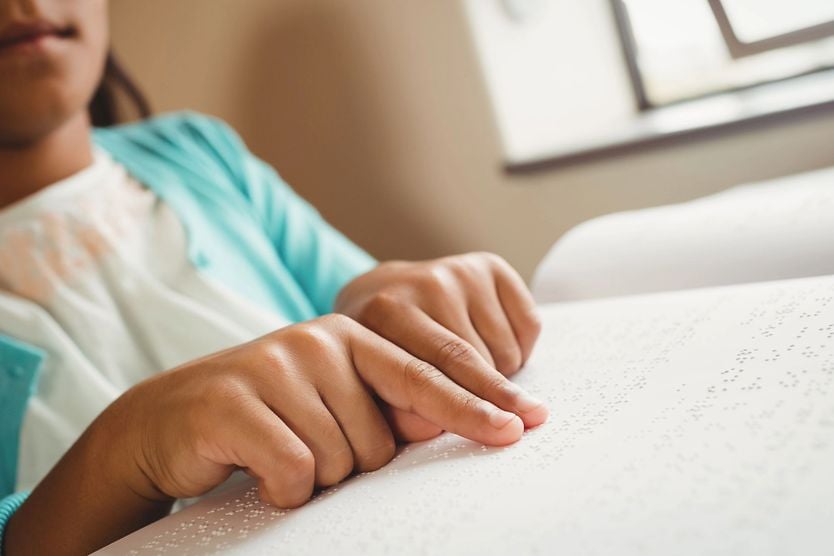 Girl using braille to read at school.