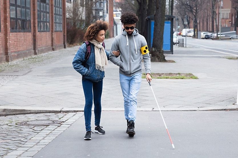 How to help someone who is visually impaired woman helping her blind friend walking with cane