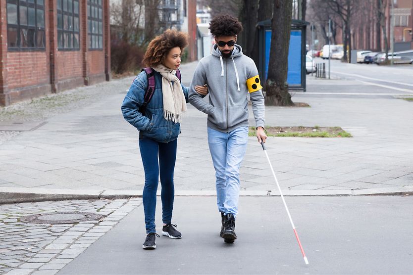 woman helping her blind friend walking with cane