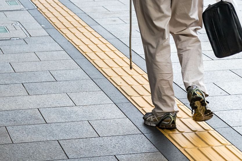 blind person walking along tactile paving
