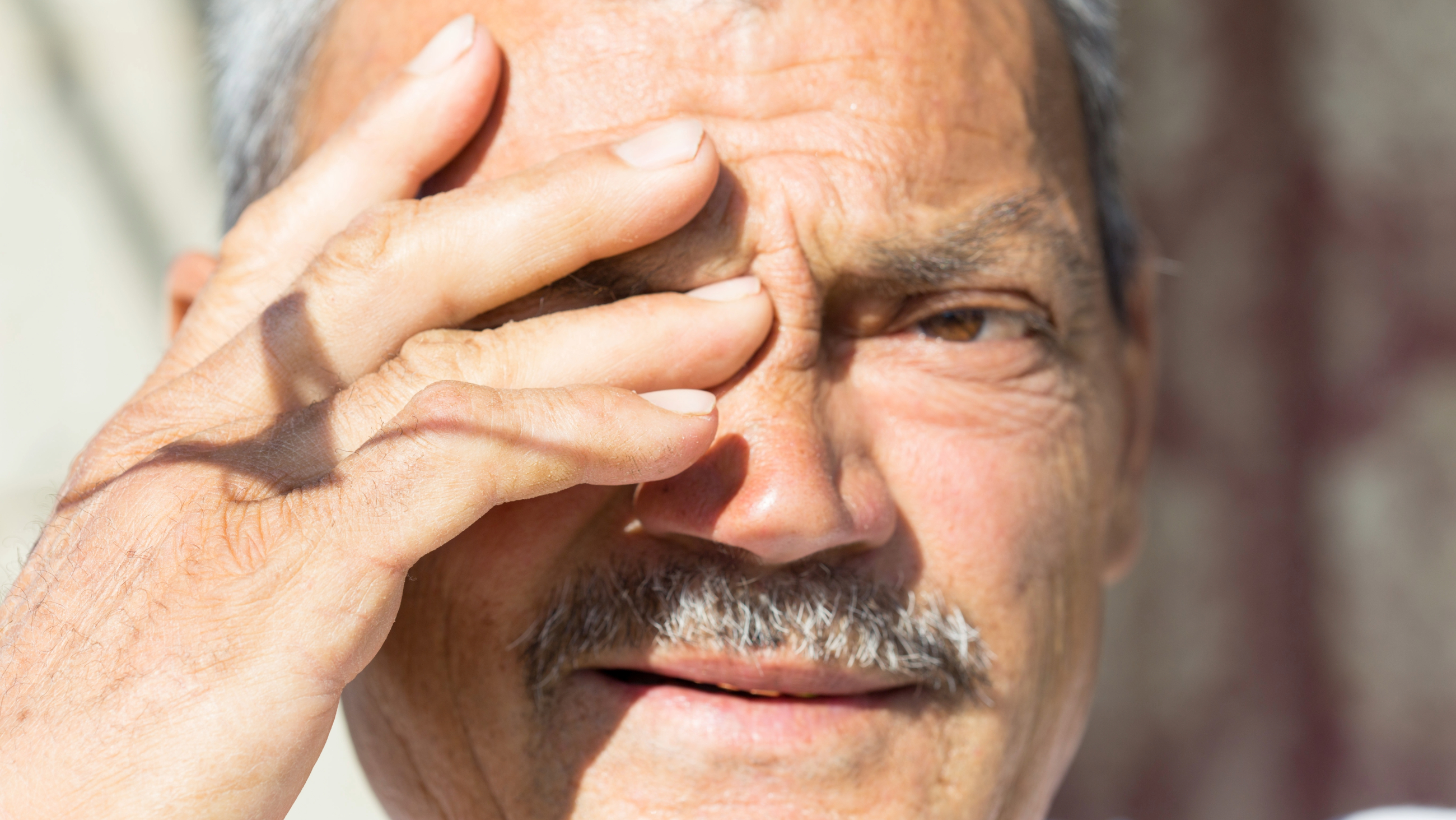 man sensitive to the bright light, which is a symptom of having cataracts