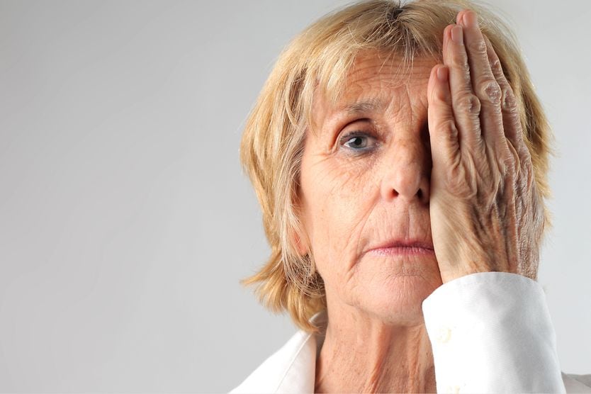 When to have a cataracts test and what to expect during the exam woman with one hand over her eye taking a visual acuity test for cataracts