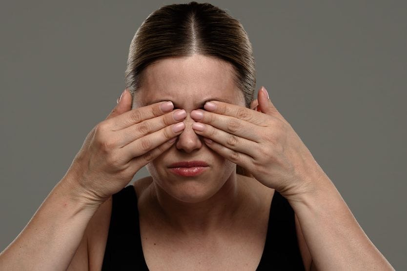 person covering eyes with hands who has staph infection in eyes