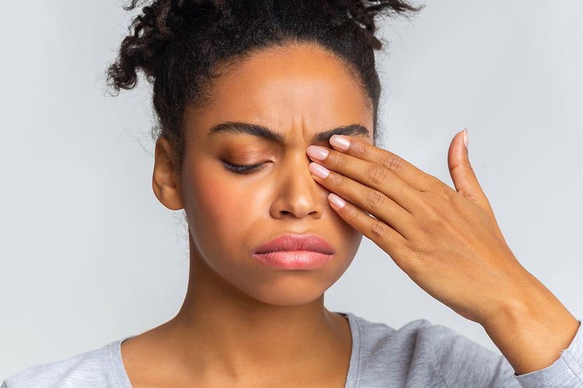 Does pink eye hurt? Woman with eyes closed from eye discomfort
