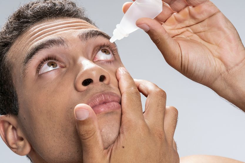 What kind of eye drops are used for pink eye? Man tilting head back to apply eye drops