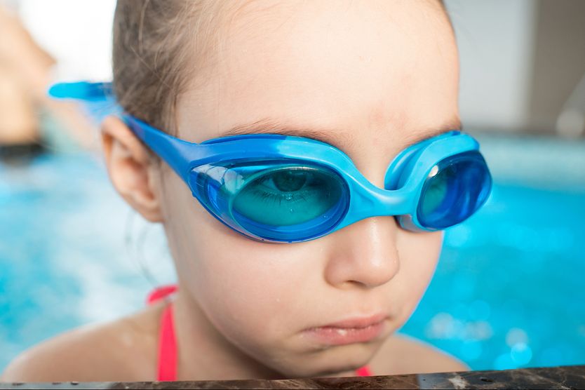 Why you should avoid swimming with pink eye Little girl wearing swim goggles looks sad at the side of a pool