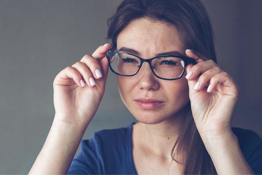 Can astigmatism cause myopia? woman squinting through her glasses with both astigmatism and myopia