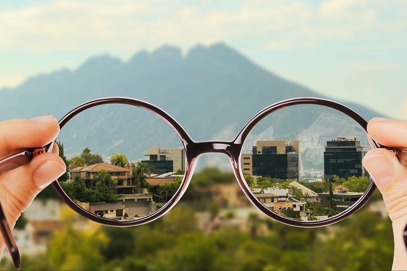 Looking through glasses at a mountain landscape, showing the difference between myopia and corrected vision through the lenses.