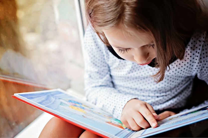 Can too much reading cause myopia in children? young girl reading a book