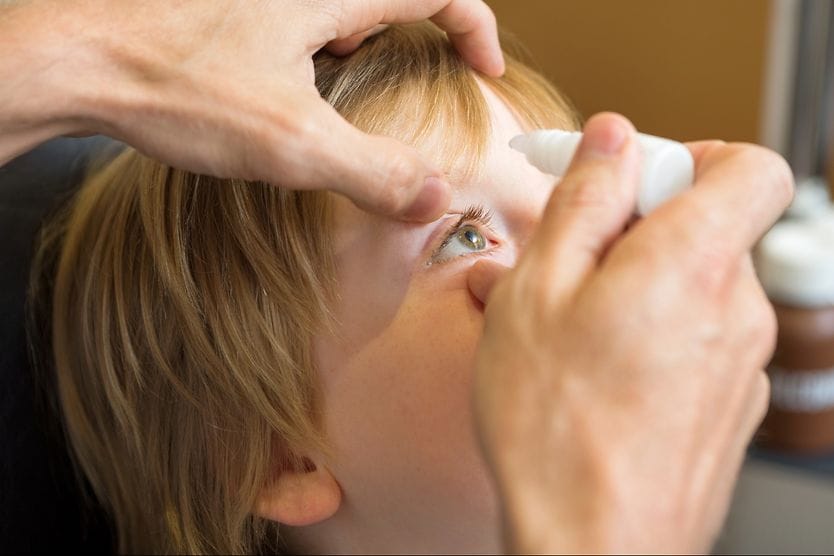 child getting atropine eye drops put into their eyes