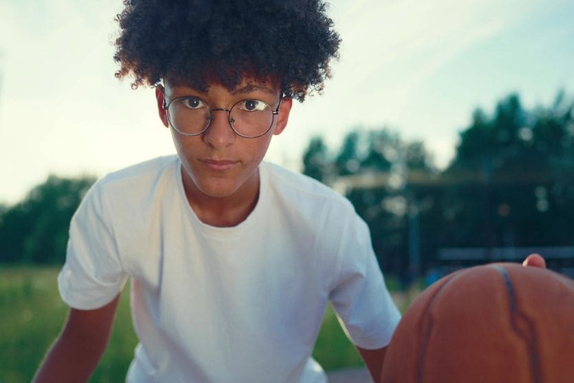 teen with myopia wearing glasses and playing basketball