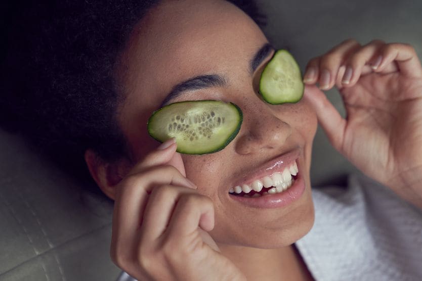 Can you fix droopy eyelids naturally? woman with droopy eyelids putting cucumber on her eyes as a home remedy