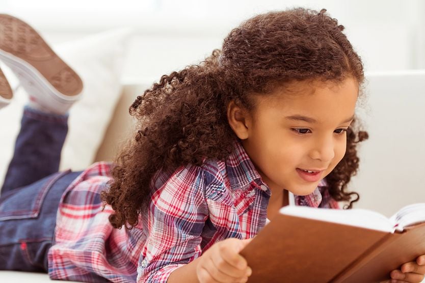 young girl reading a book experiencing convergence insufficiency