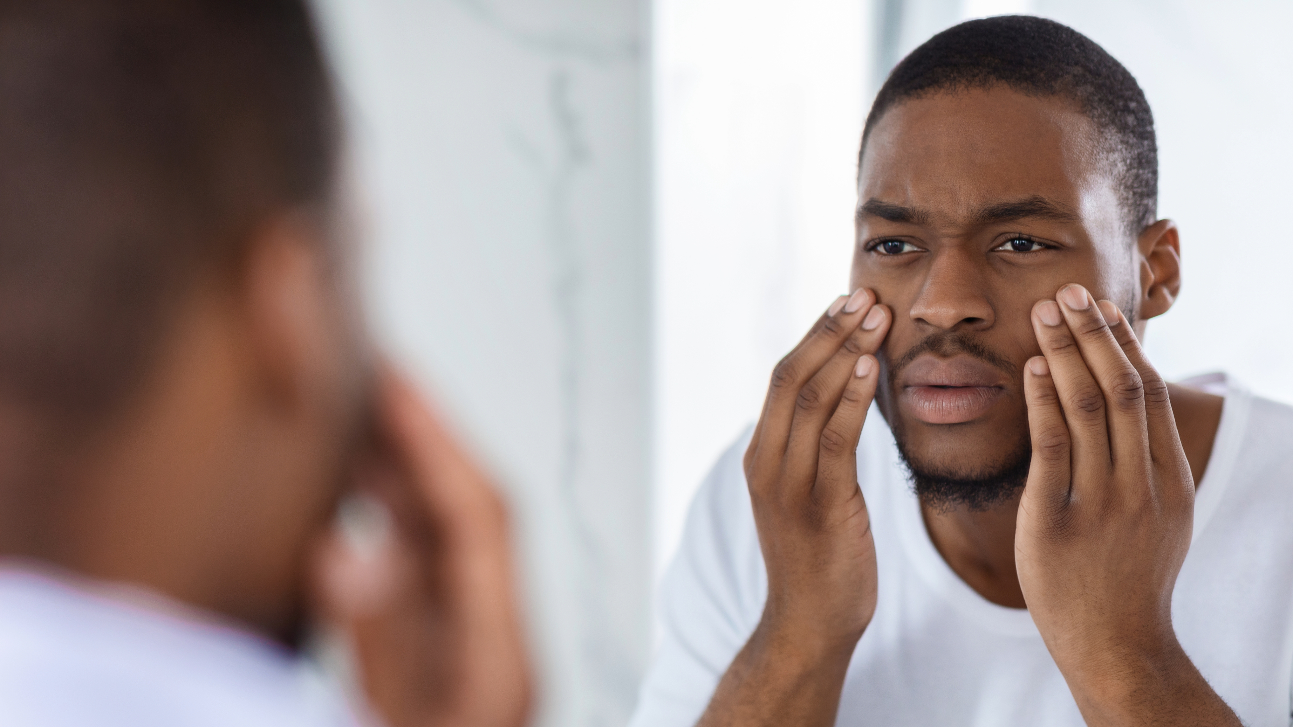 man with glassy eyes looking in the mirror