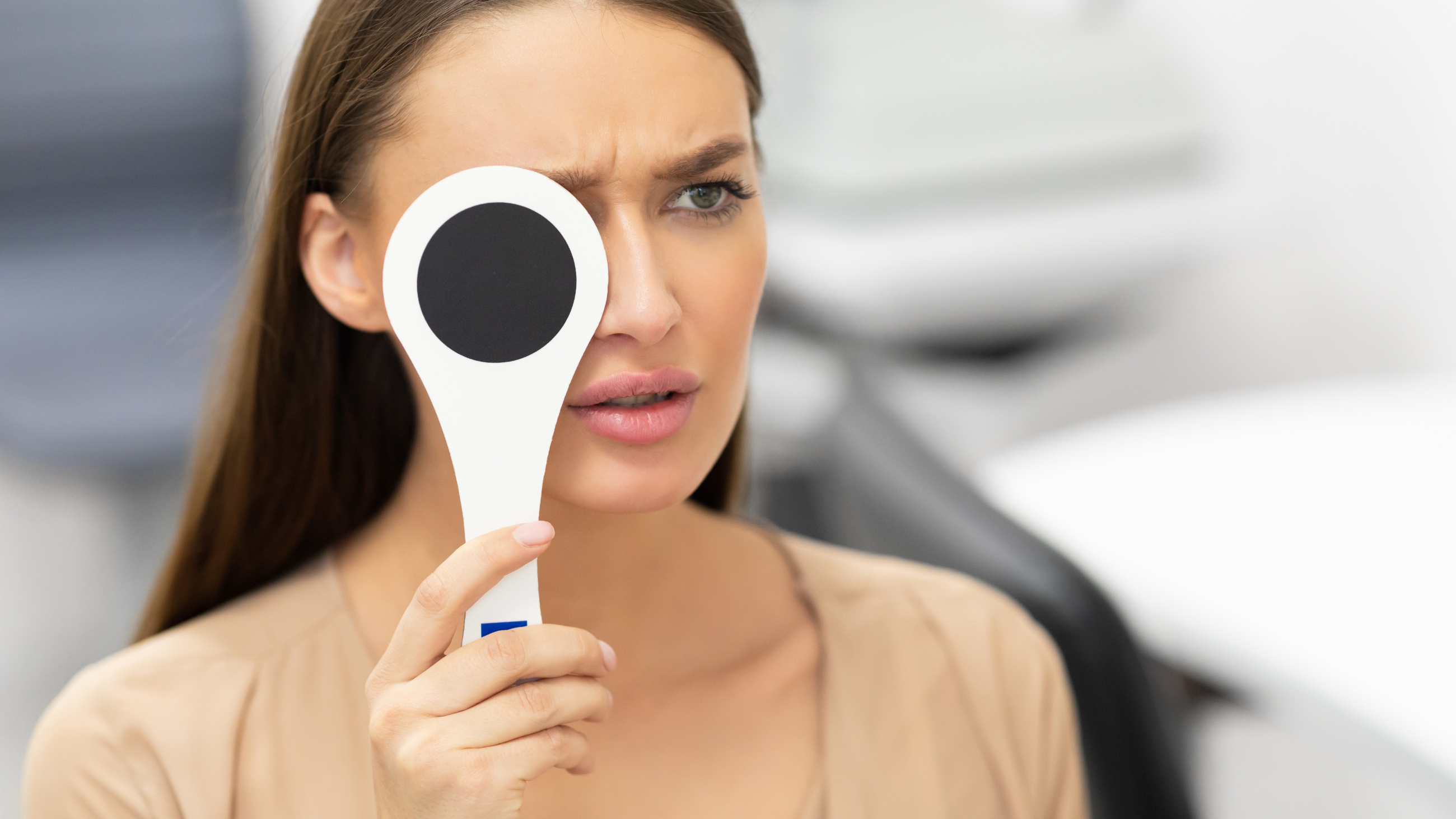 woman with blurry vision in one eye covering the other eye