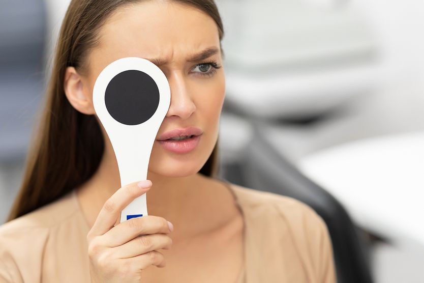 woman with blurry vision in one eye covering the other eye
