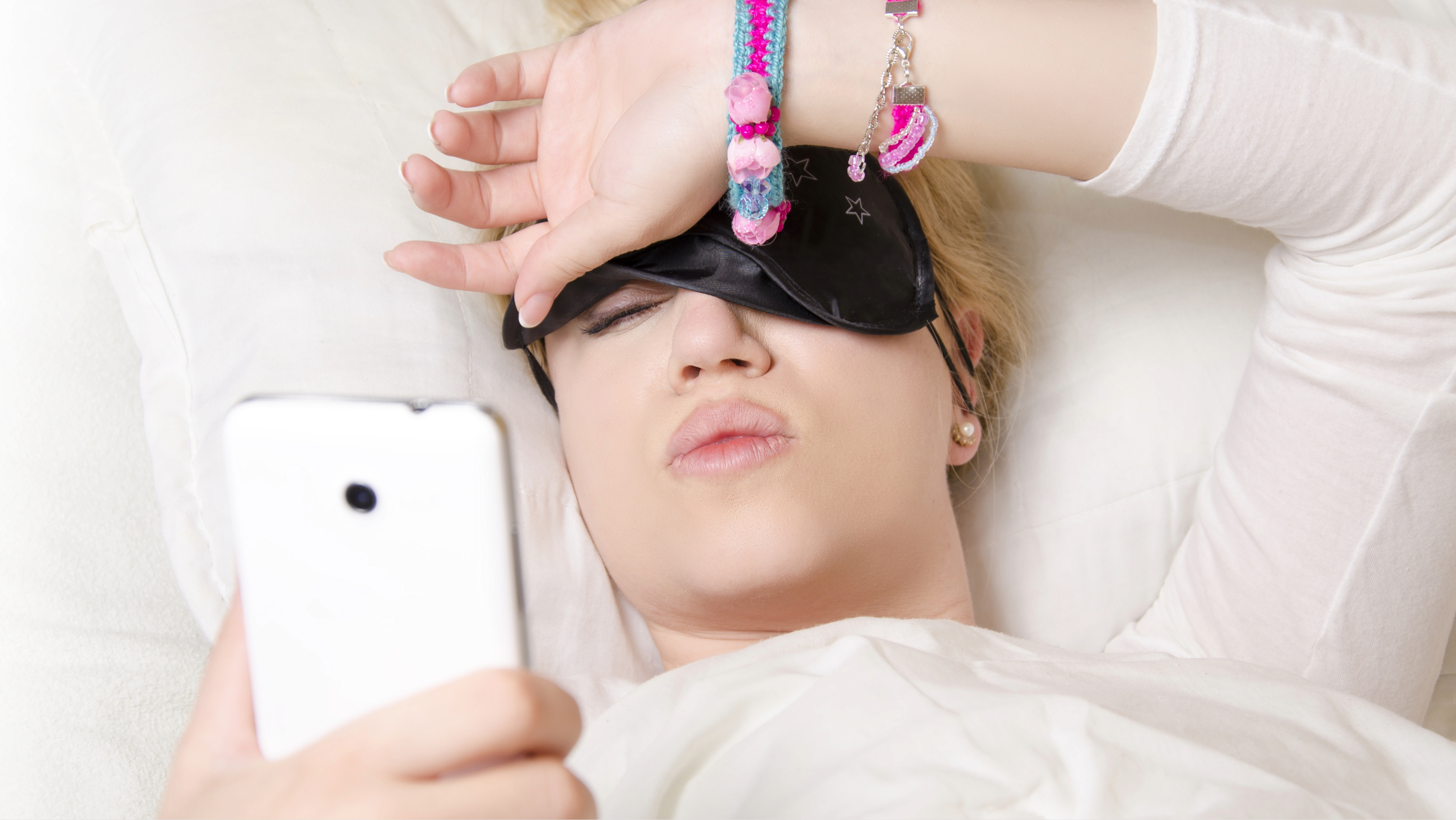 woman waking up in the morning with blurry vision looking at cell phone