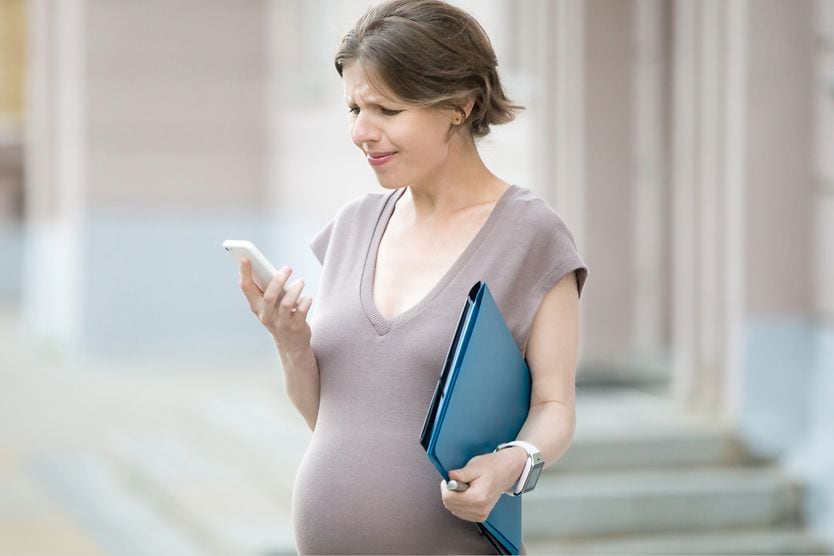 Pregnant woman with blurry vision looking at her cell phone
