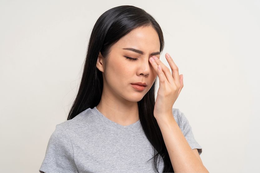 Woman has fingers over eye due to burning sensation