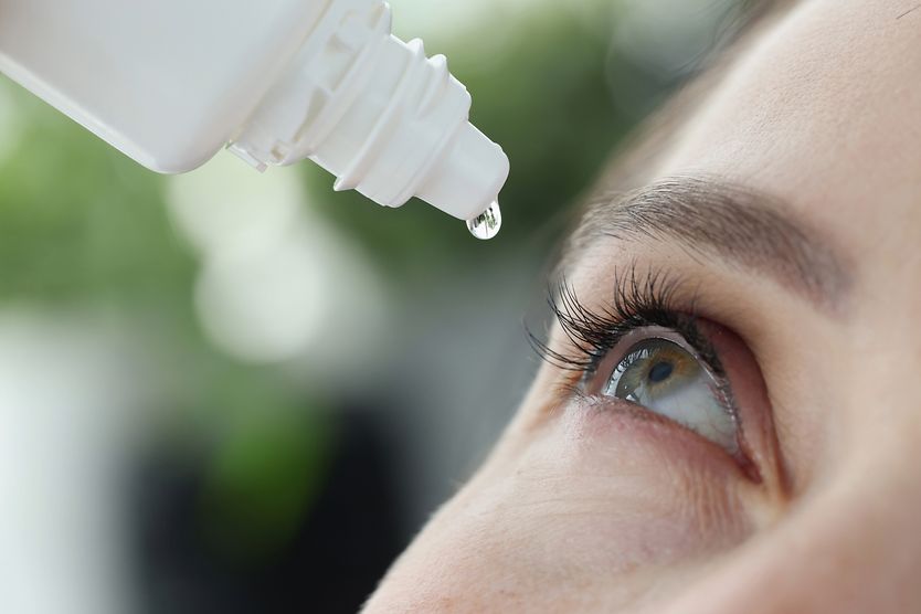 Eye drops and other treatments for eye twitching close up of woman using eye drops