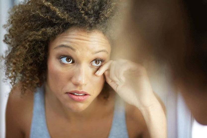Can fake eyelashes cause eye infections? woman looking in the mirror with fake eyelashes and an eye infection