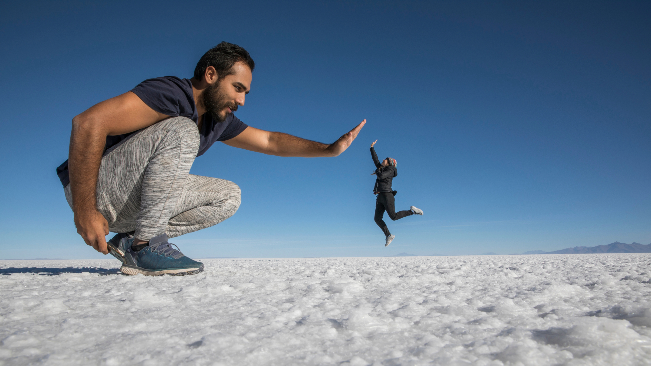 Optical illusion of giant man and small woman high-fiving.