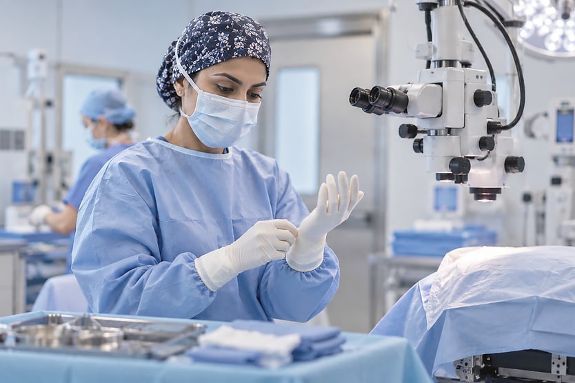 Ophthalmologist Preparing for Eye Surgery Ophthalmologist in surgical scrubs and gloves preparing equipment in an operating room.