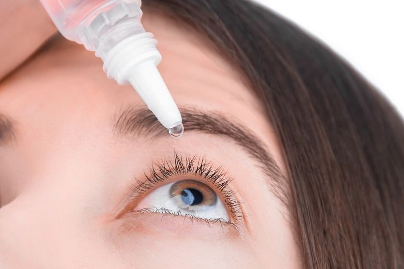 Artificial tears solution: Uses, side effects and dosage Young woman placing artificial tear into eye.