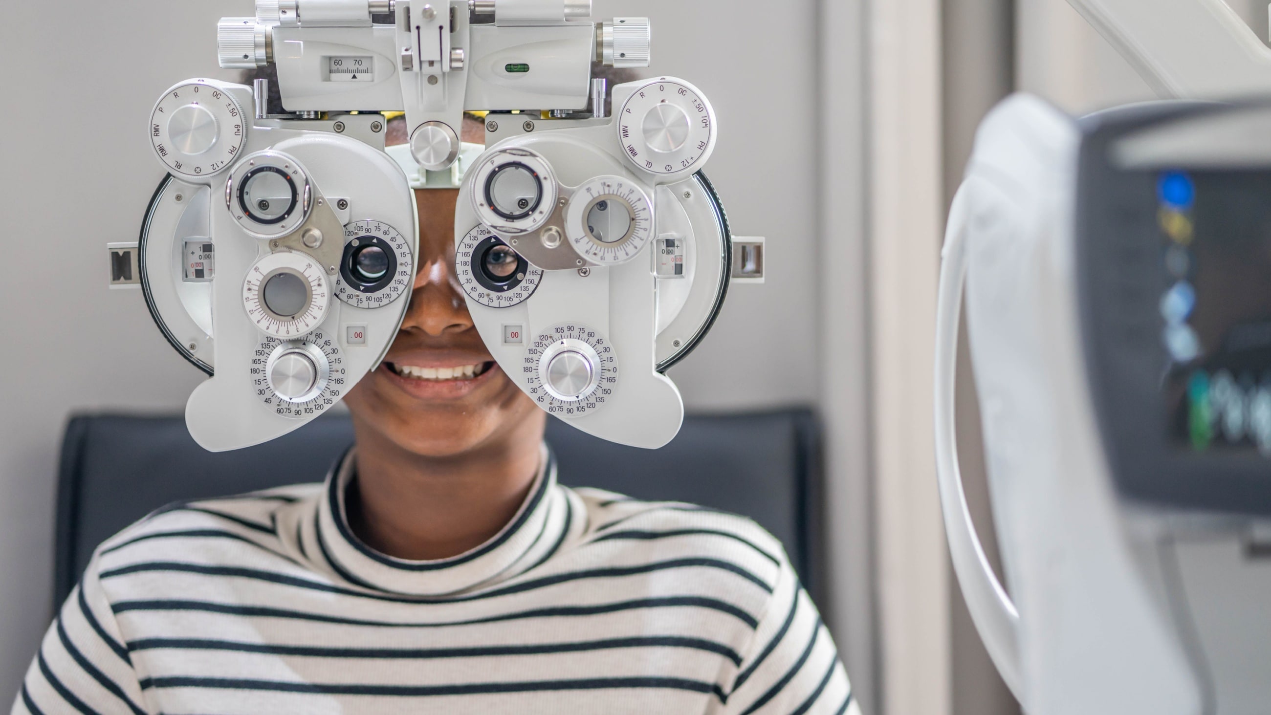 man looking through a phoropter with 20/15 vision