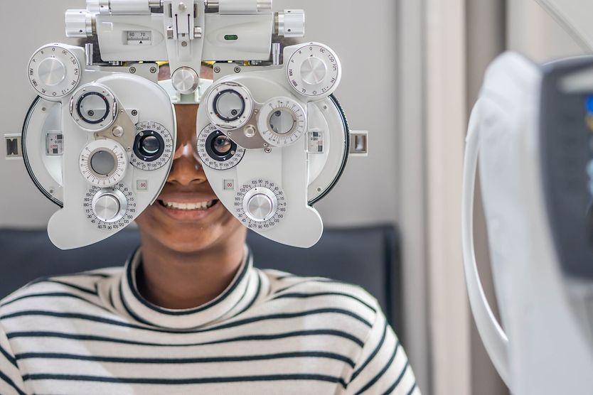 20/15 vision: Better or worse than 20/20? man looking through a phoropter with 20/15 vision