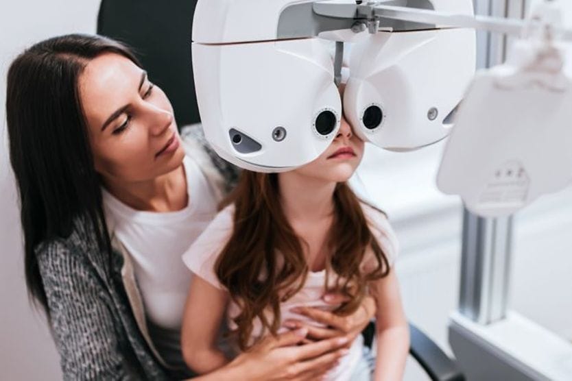 What is 20/20 vision? Girl sitting on her mother's lap to perform eye test and define her visual acuity