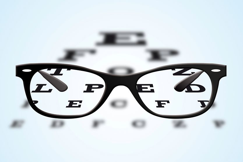 Eyeglasses with black frames positioned on an ophthalmic eye test table