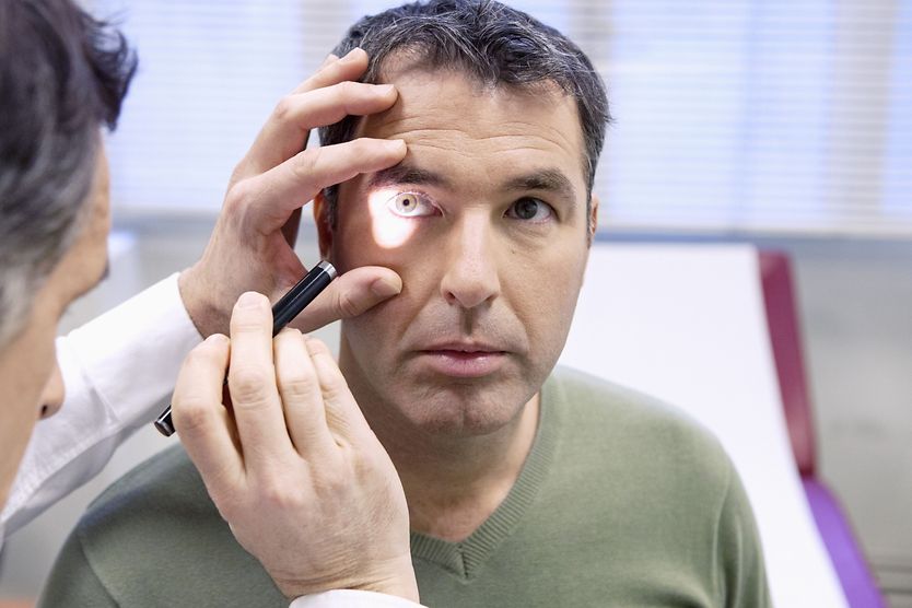 eye doctor performing a perrla eye test on patient