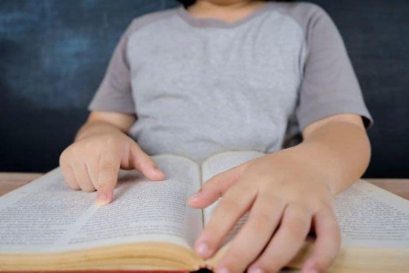 How do I know if my child needs glasses? child reading book with finger