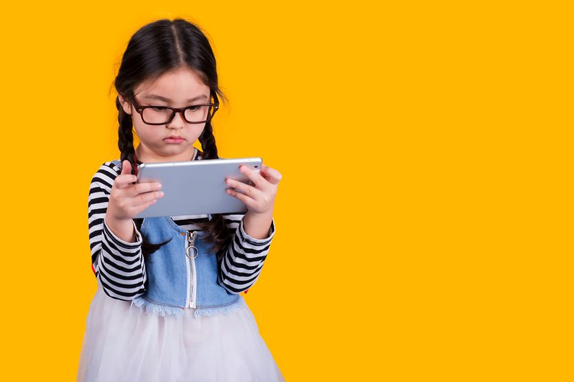 How you can improve your kid’s vision young girl wearing eyeglasses looking at her mobile phone