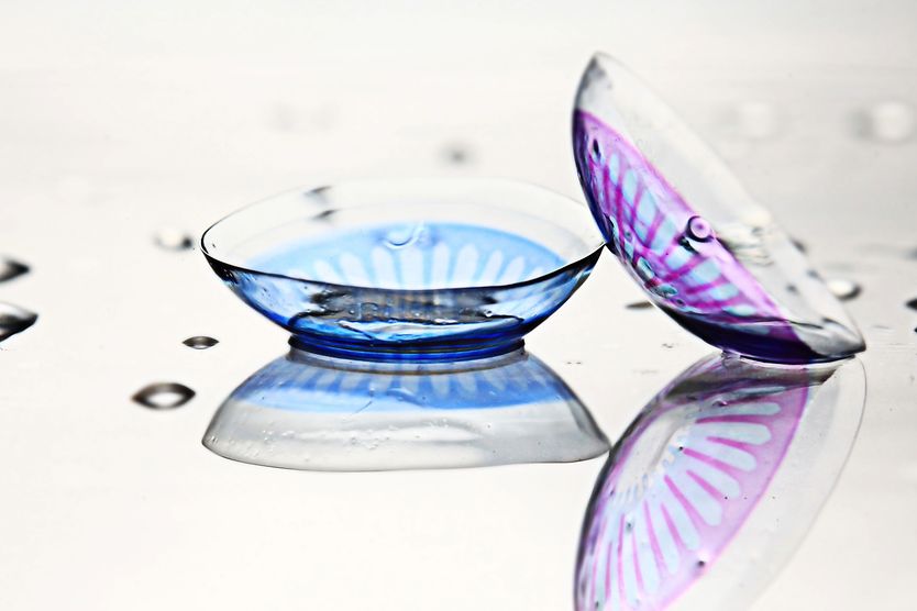 Two colored contact lenses, one for blue eyes and one for purple eyes.