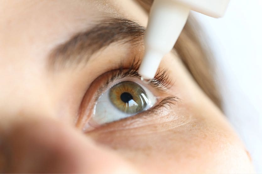 Close-up of young woman applying eye drop.