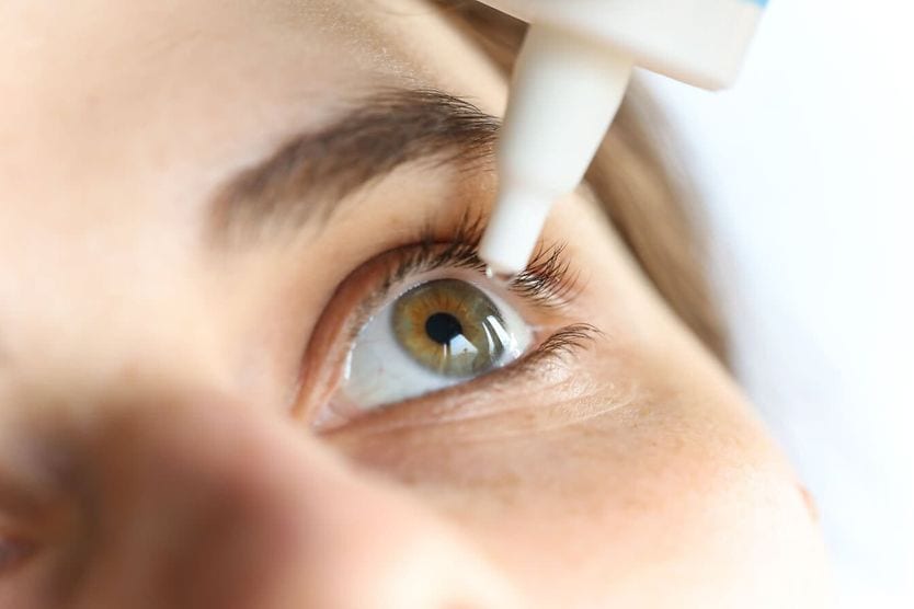 Can you use contact solution as eye drops? Close-up of young woman applying eye drop.