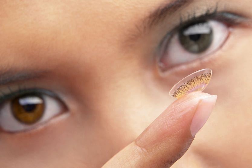 woman putting in colored contacts for her astigmatism