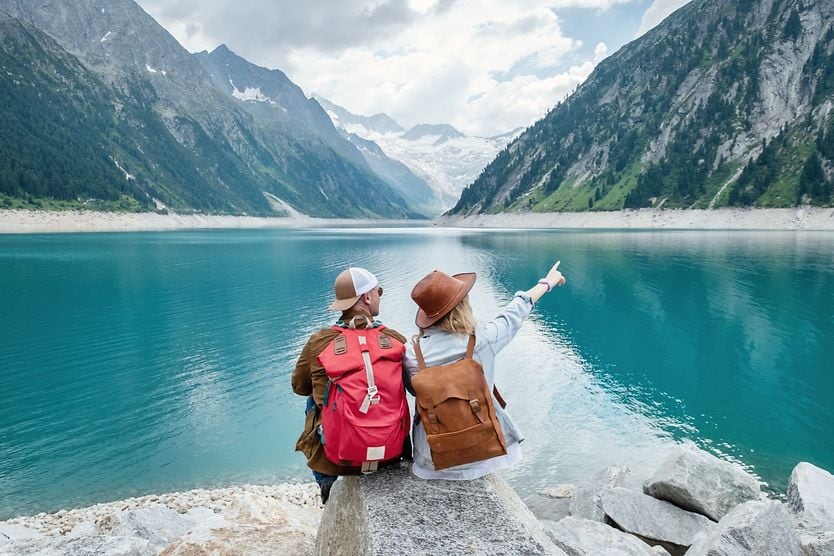 Everything you need to know about traveling with contact lenses People sitting on rock, looking out at lake and mountains.