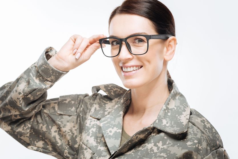 A smiling woman in a military uniform wearing glasses.