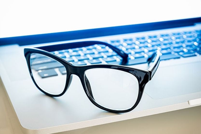 Pair of blue light eyeglasses sitting on a laptop